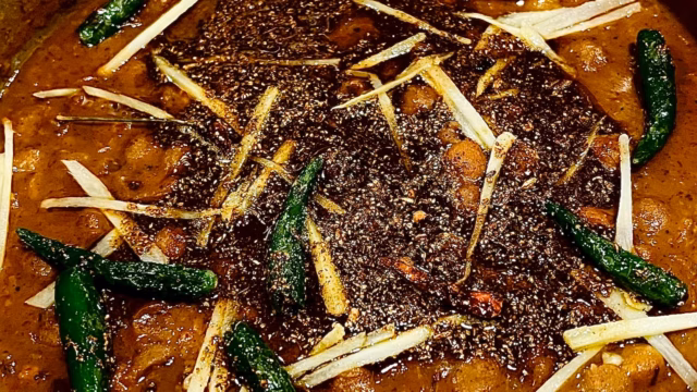 Close-up of Koyla's Indian Smokehouse and Bar's northern Indian cuisine, filled with spices, peppers, and orange sauce.