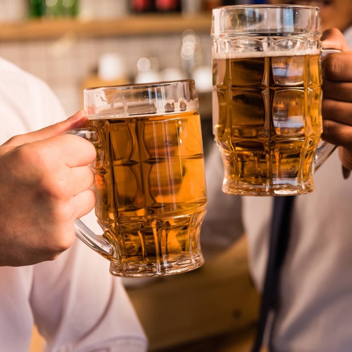 cropped shot of businessmen clinking beer glasses in bar