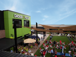 Chicken N Pickle exterior with people milling around the outdoor seating area.