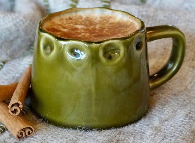 Hot latte in a green ceramic mug with cinnamon sticks at Armor Coffee in Allen, Texas.