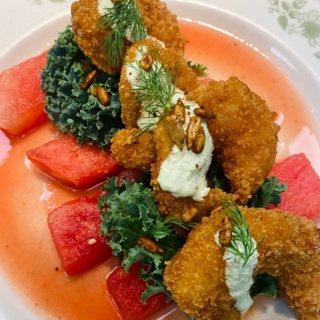 Fried shrimp with poblano pickle cream, kale, dill and spiced sunflower seeds served over watermelon aguachile at Harvest in McKinney, Texas.