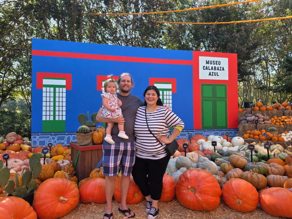 Family with a young child poses among colorful pumpkin displays during Autumn at the Arboretum at the Dallas Arboretum.