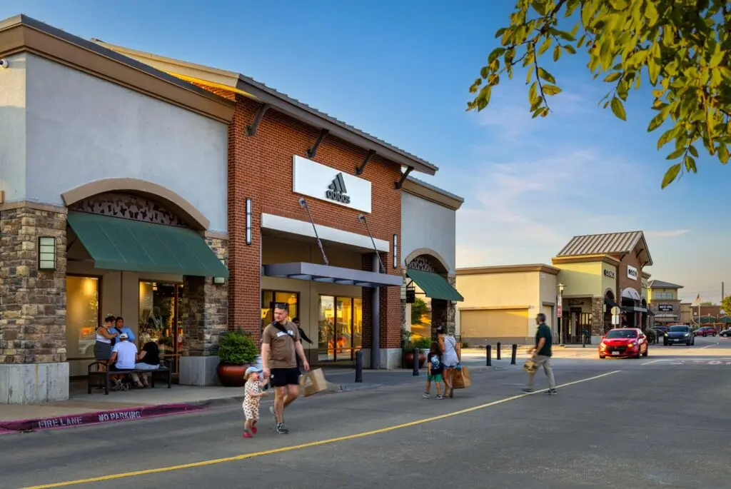 Shoppers walking between storefronts at Allen Premium Outlets in Allen, Texas.