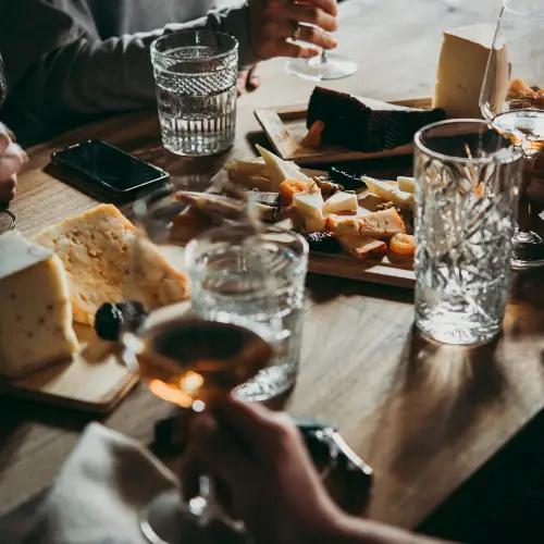 dinner table with glasses of wine and water surrounding a charcuterie board spread