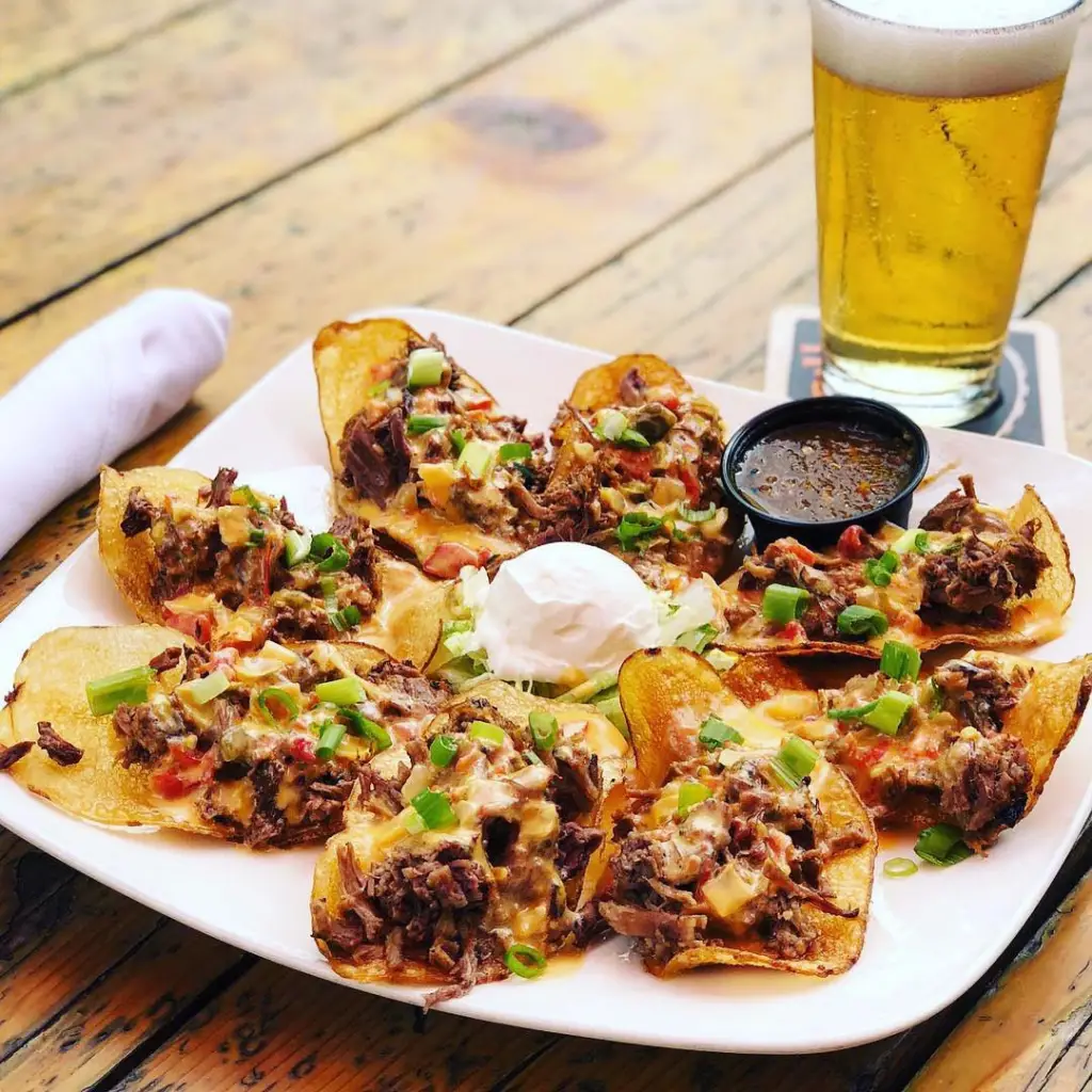 Loaded nachos topped with shredded beef, cheese, and green onions served with a beer
