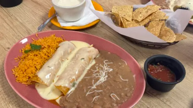 Tex-Mex plate with cheese enchiladas, rice, refried beans, chips, salsa, and queso.