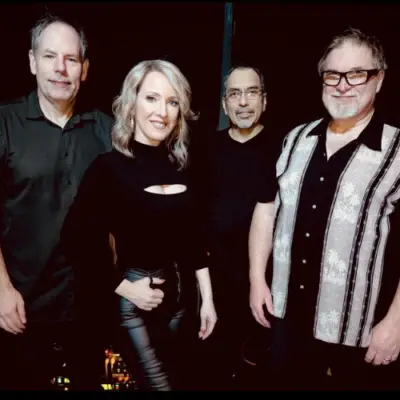 Four-member band posing together in dark attire for a live music event in Allen, Texas