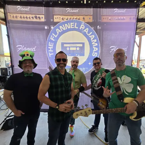 Members of The Flannel Pajamas band posing with instruments in front of a branded backdrop.