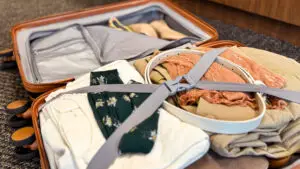 Open suitcase packed with neutral clothing, layered outfits, and accessories for intentional travel packing.