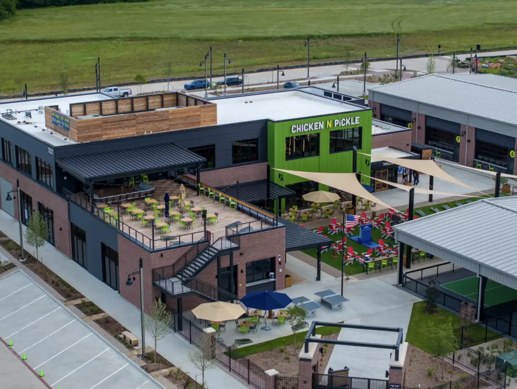 Aerial view of the Chicken N Pickle venue featuring outdoor patios and pickleball courts.