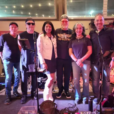 Members of Chasing Angels posing together on stage during a live music performance in front of microphones and band equipment.