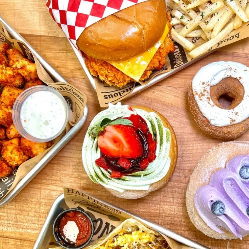 Crispy chicken sandwich with fries next to three colorful, decorated gourmet donuts.