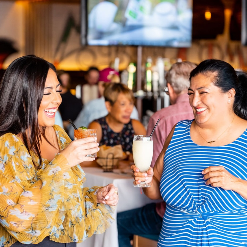Two guests enjoying cocktails and conversation inside Mexican Bar Company, a new Mexican restaurant coming to Allen, Texas.