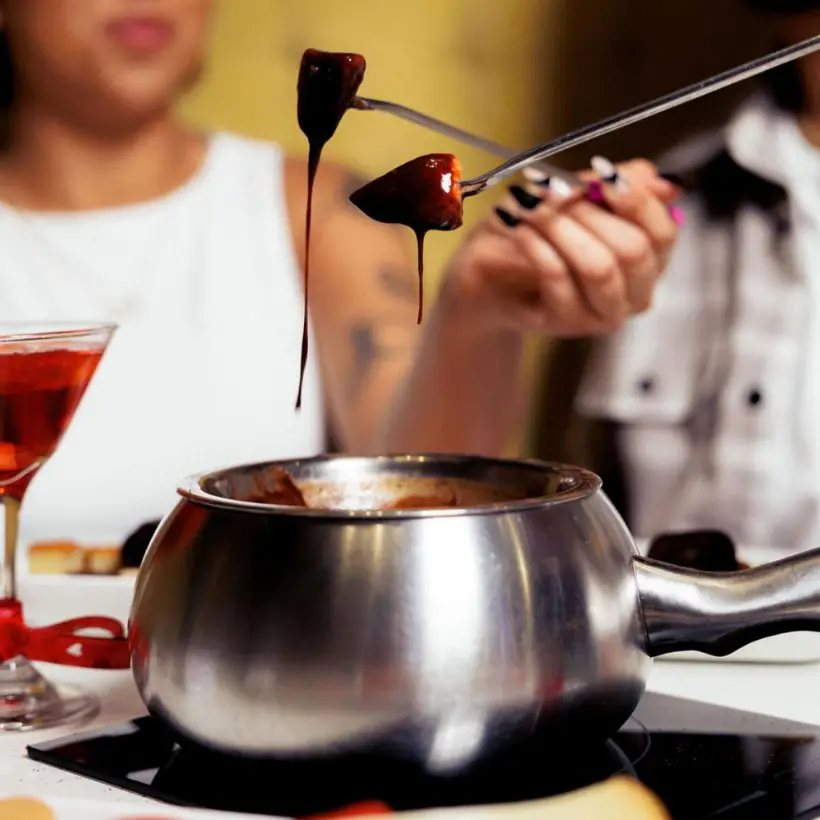 Guests dipping strawberries into chocolate fondue at The Melting Pot, opening at Watters Creek Village in Allen, Texas.