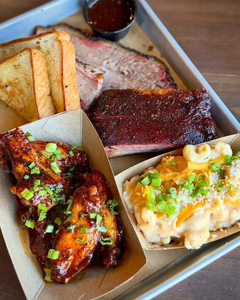 Barbecue tray with smoked ribs, sliced brisket, mac and cheese, and glazed wings from Vaqueros Texas Bar-B-Q.