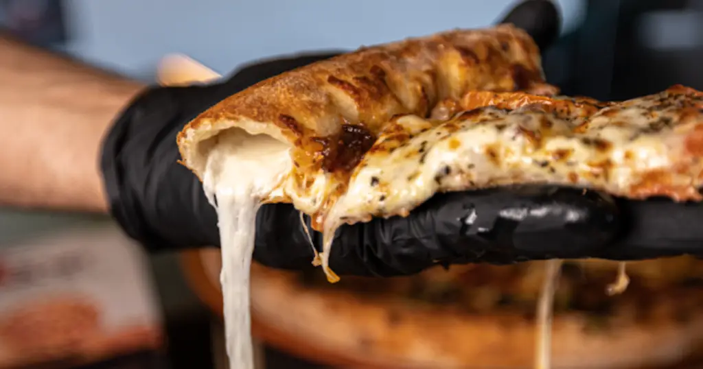 Close-up of a cheesy slice of pizza being served at Zio Al's Signature, an Italian restaurant in Allen, Texas.