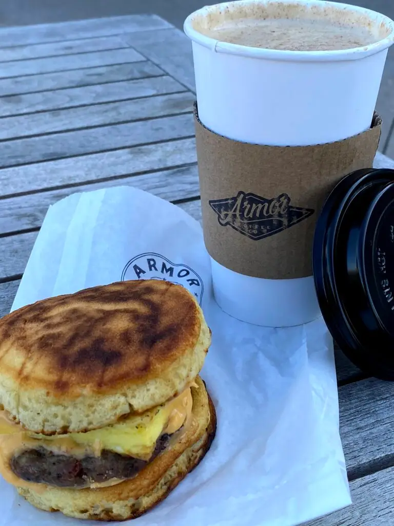 Breakfast from Armor Coffee in Allen, Texas, featuring a croissant, breakfast sandwich, and coffee enjoyed on the café's outdoor patio.