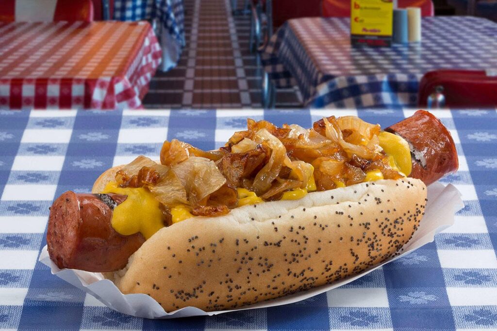 A Portillo's chili cheese dog topped with chili, melted cheese, and grilled onions is served on a poppy seed bun inside Portillo's in Allen, Texas.
