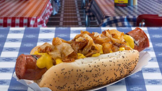 A Portillo's chili cheese dog topped with chili, melted cheese, and grilled onions is served on a poppy seed bun inside Portillo's in Allen, Texas.