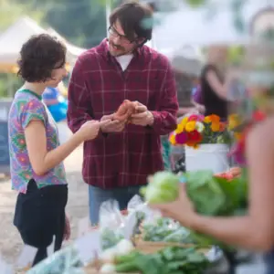 Two shoppers browse fresh produce and flowers from local vendors at The Market at The Village at Allen in Allen, Texas.