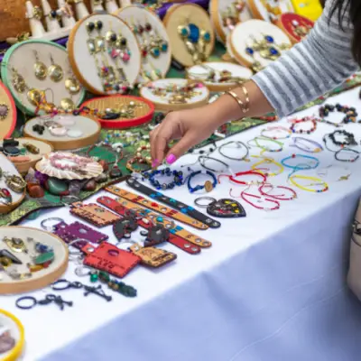 A shopper browses handmade jewelry and artisan accessories at a vendor booth during The Market at The Village at Allen in Allen, Texas.