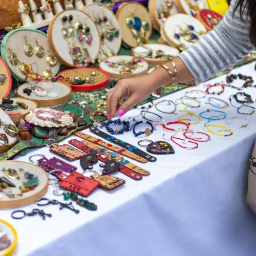 A shopper browses handmade jewelry and artisan accessories at a vendor booth during The Market at The Village at Allen in Allen, Texas.