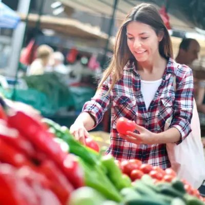 A shopper selects fresh red peppers at The Market at The Village at Allen in Allen, Texas, while browsing locally grown produce.