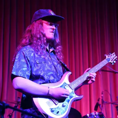 A guitarist performs on stage during a live performance by Travelin' Jed.