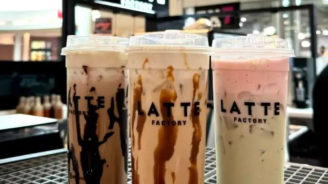Three iced specialty drinks from Latte Factory are displayed on the counter inside the café at Allen Premium Outlets in Allen, Texas.