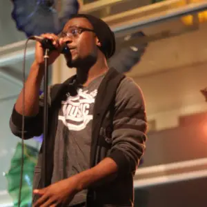 Chima Ijeh sings into a microphone during a live performance.