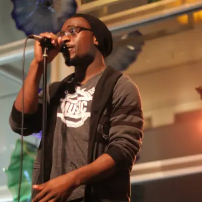 Chima Ijeh sings into a microphone during a live performance.