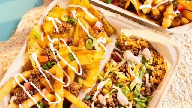 Trays of loaded fries and a rice bowl from Barrio Burrito Bar topped with seasoned ground beef, cheese sauce, lettuce, tomatoes, green onions and creamy sauces.