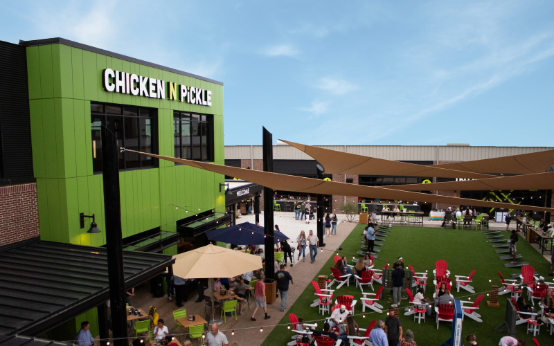 Chicken N Pickle exterior with people milling around the outdoor seating area.