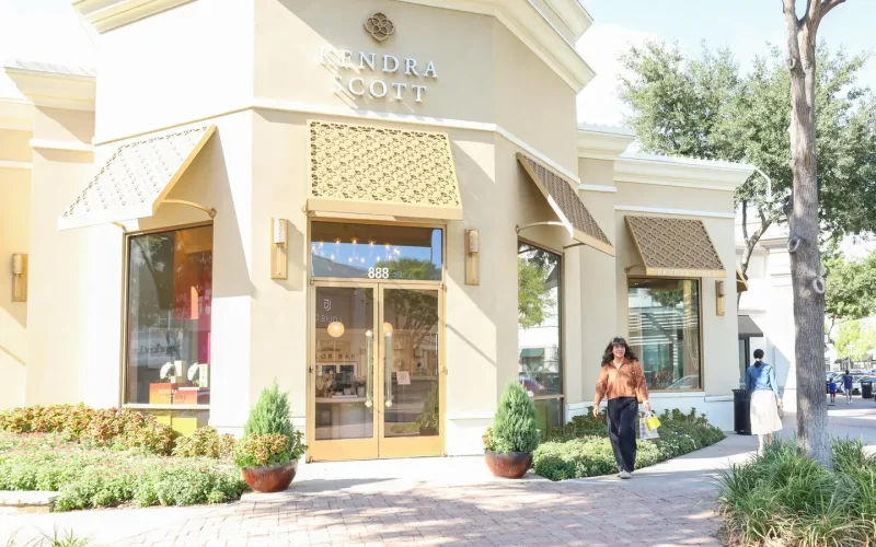 Exterior of Kendra Scott at Watters Creek Village in Allen, Texas with shopper walking along the tree-lined sidewalk.